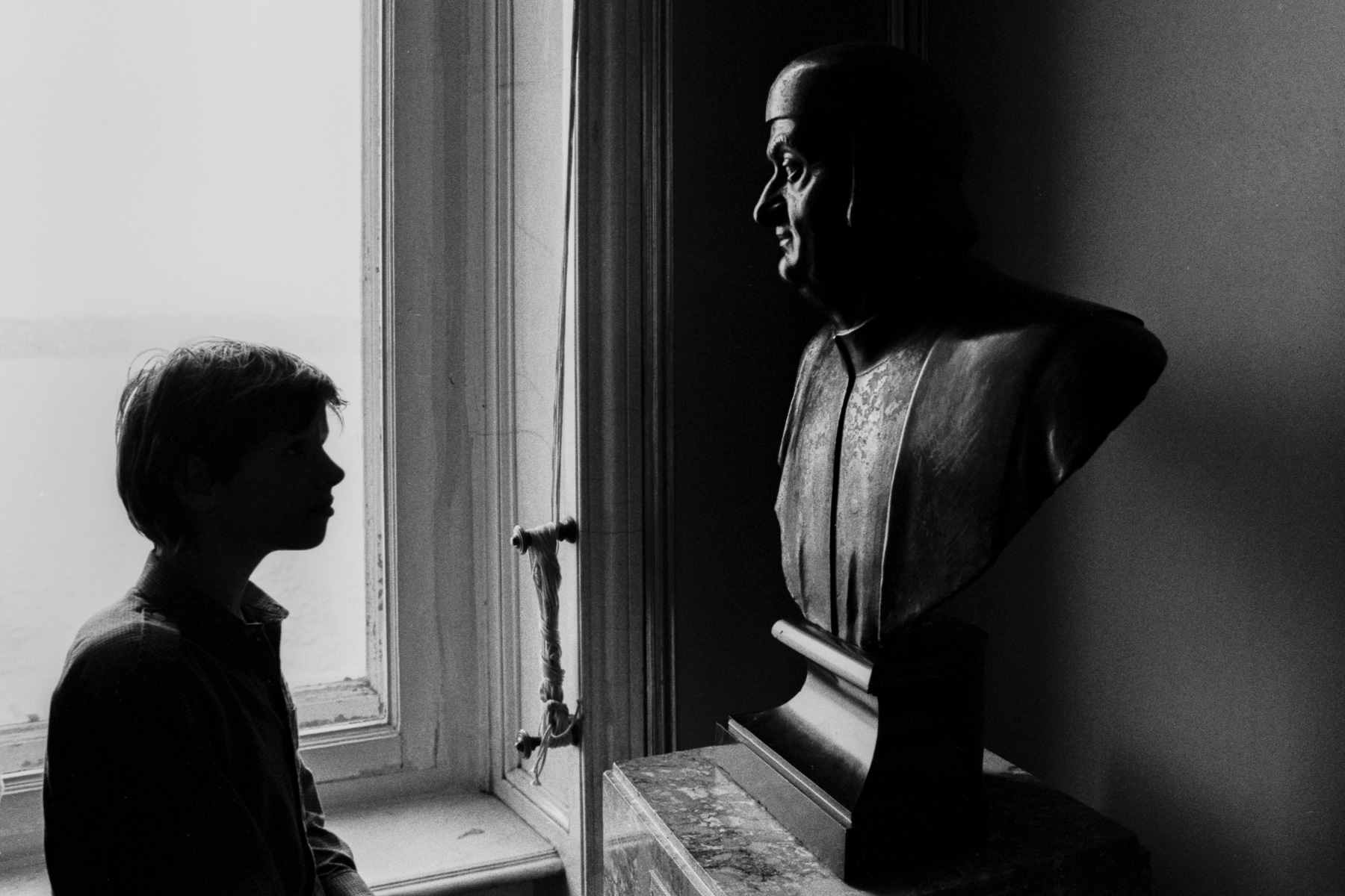Silhouette d’un enfant devant un buste dans une lumière de fenêtre