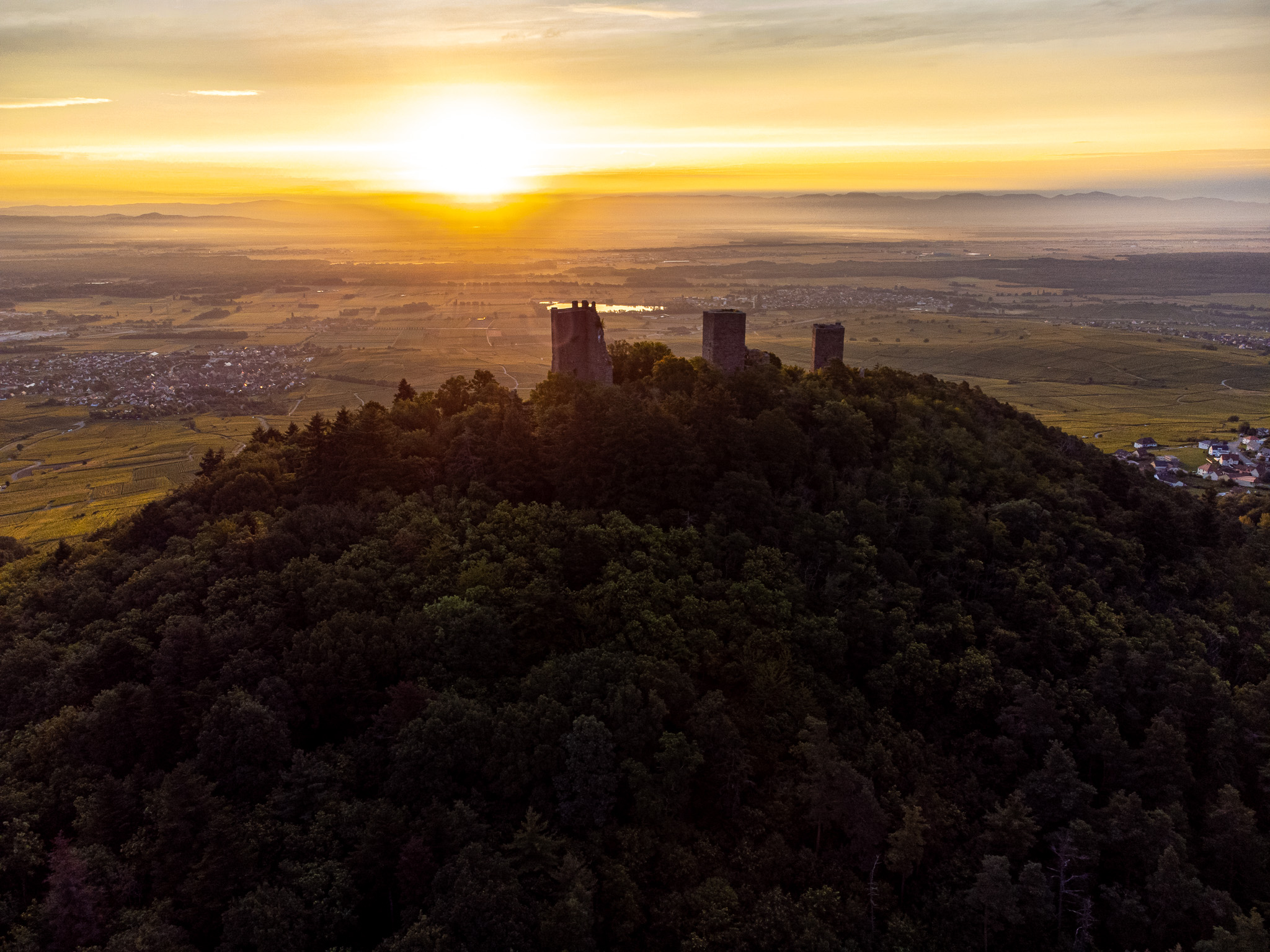 Vue aérienne d’une forteresse en ruine sur une crête boisée au lever du soleil