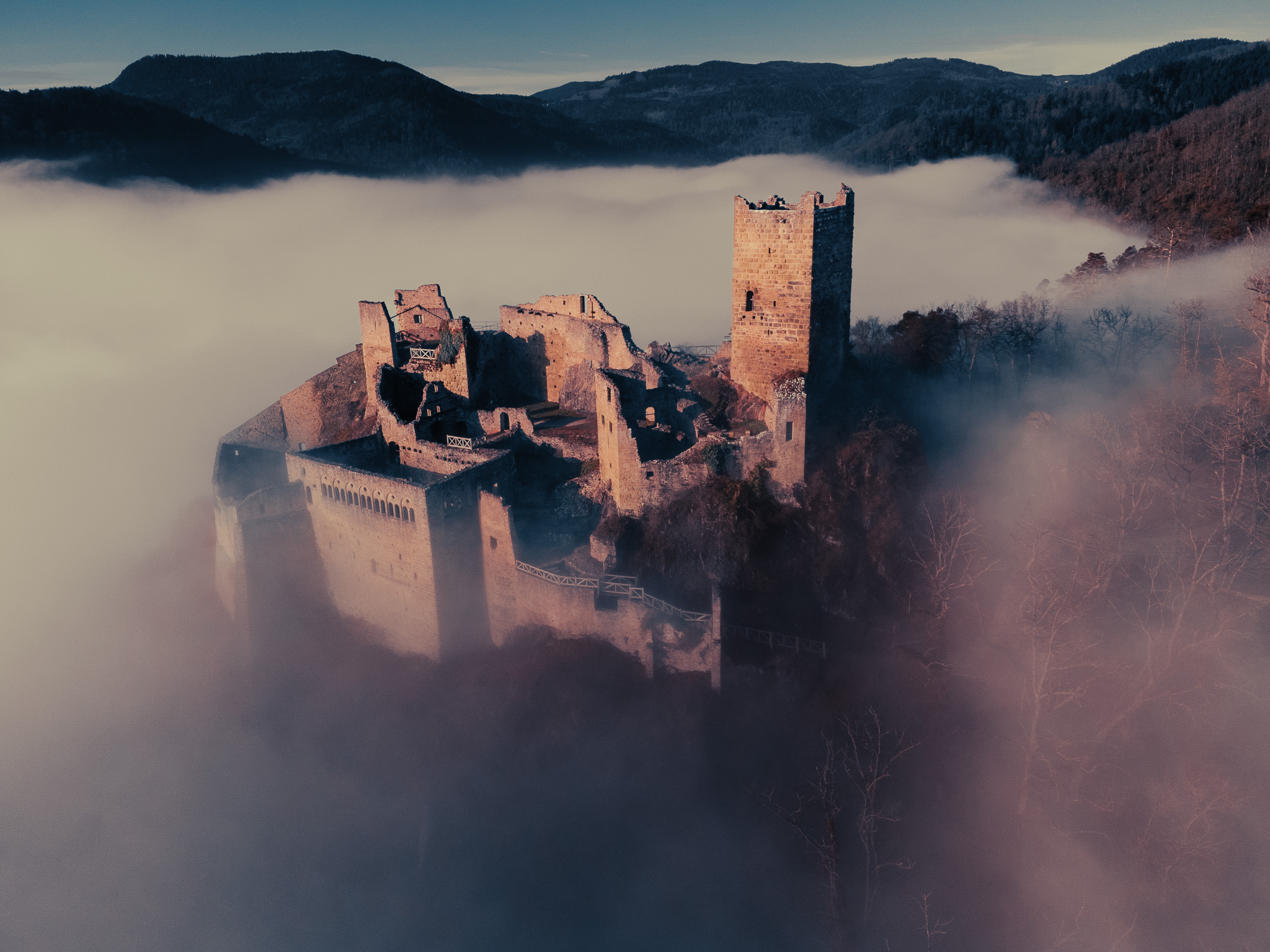 Vue aérienne du château Saint-Ulrich en ruine émergeant d’une mer de nuages en Alsace
