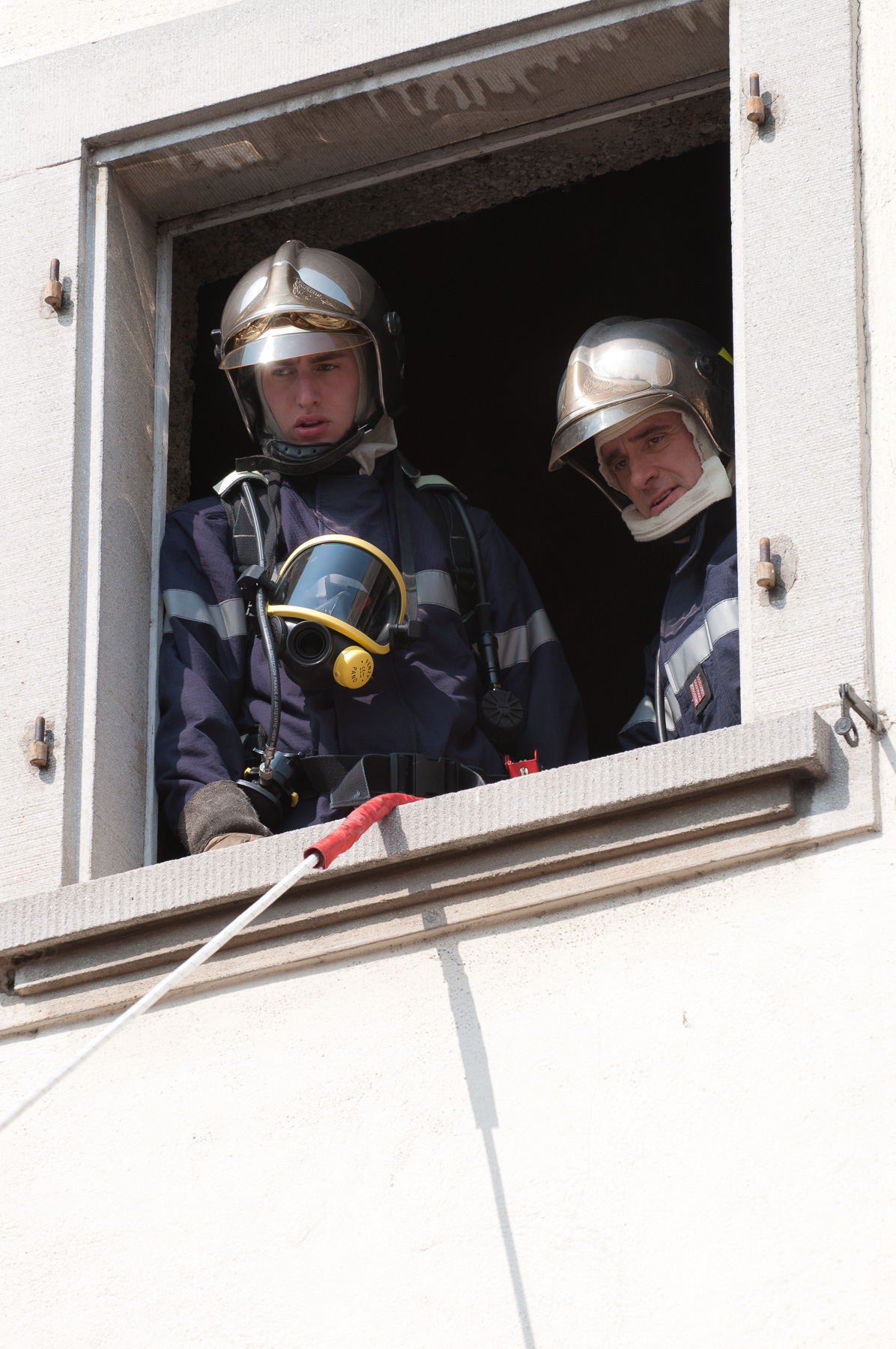 Sapeurs-pompiers visibles derrière une fenêtre lors d’un exercice