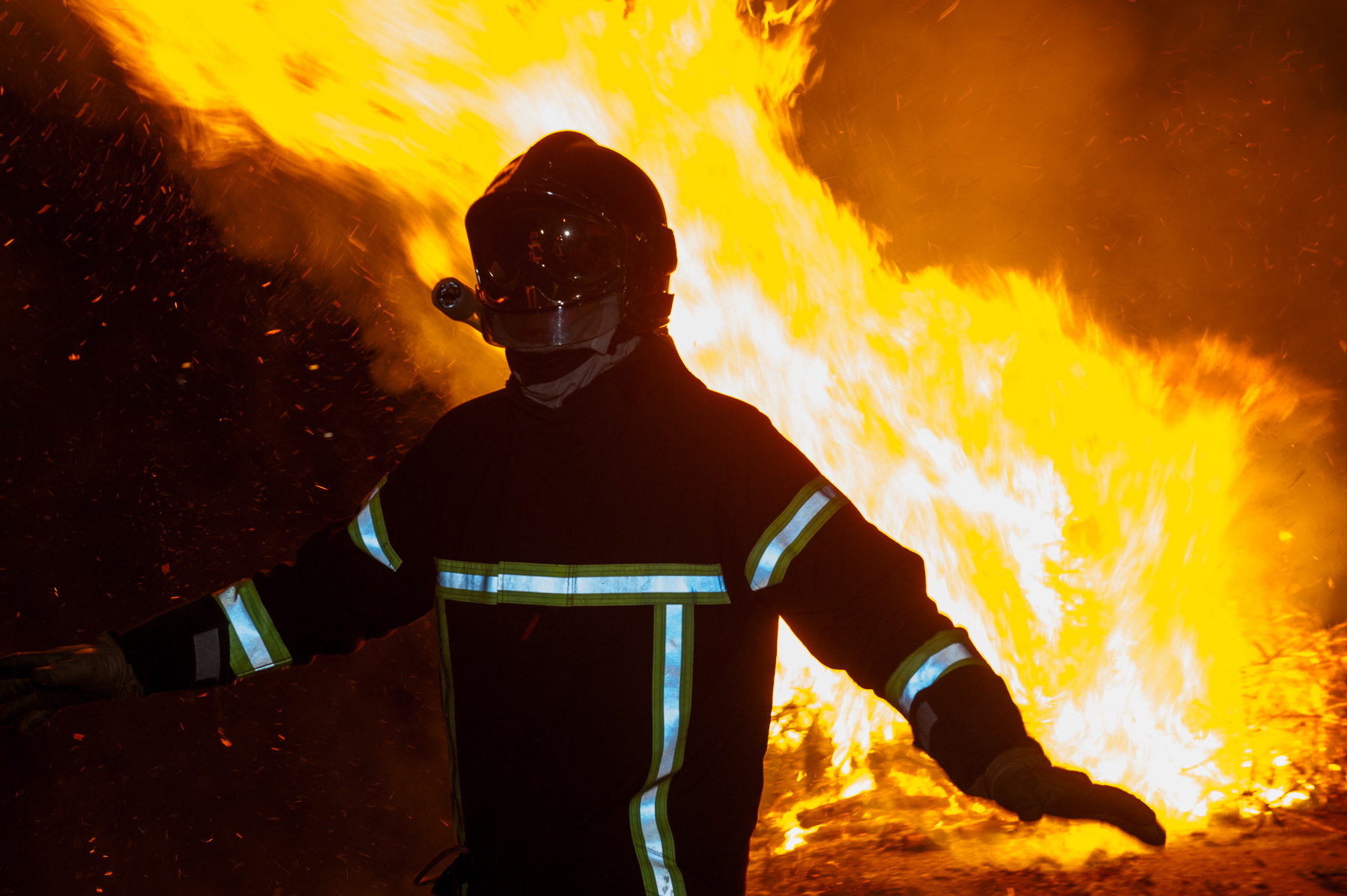 Sapeur-pompier maîtrisant un feu lors d’un exercice nocturne