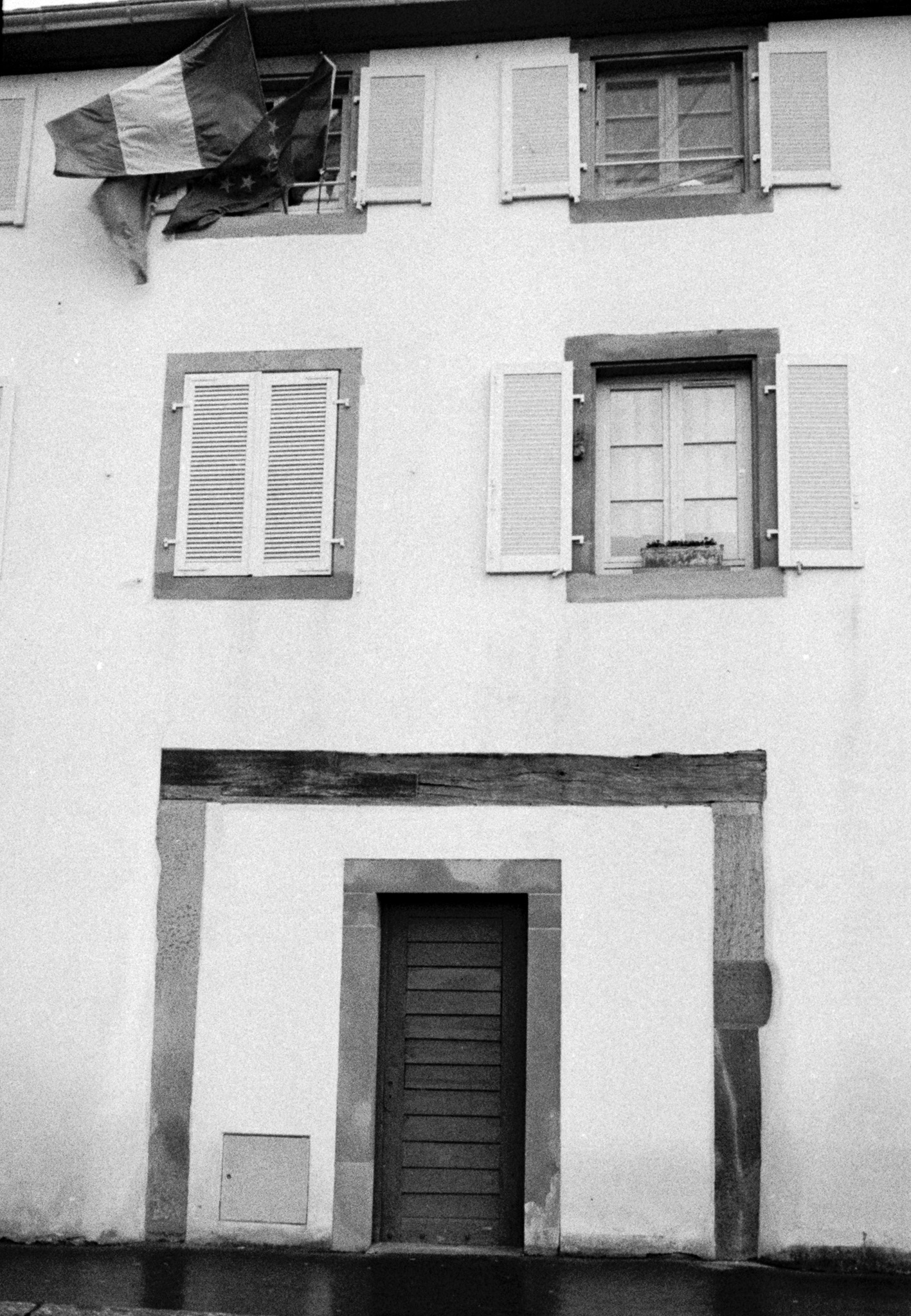 Façade d’habitation blanche avec des drapeaux français et européens suspendus à une fenêtre à Strasbourg