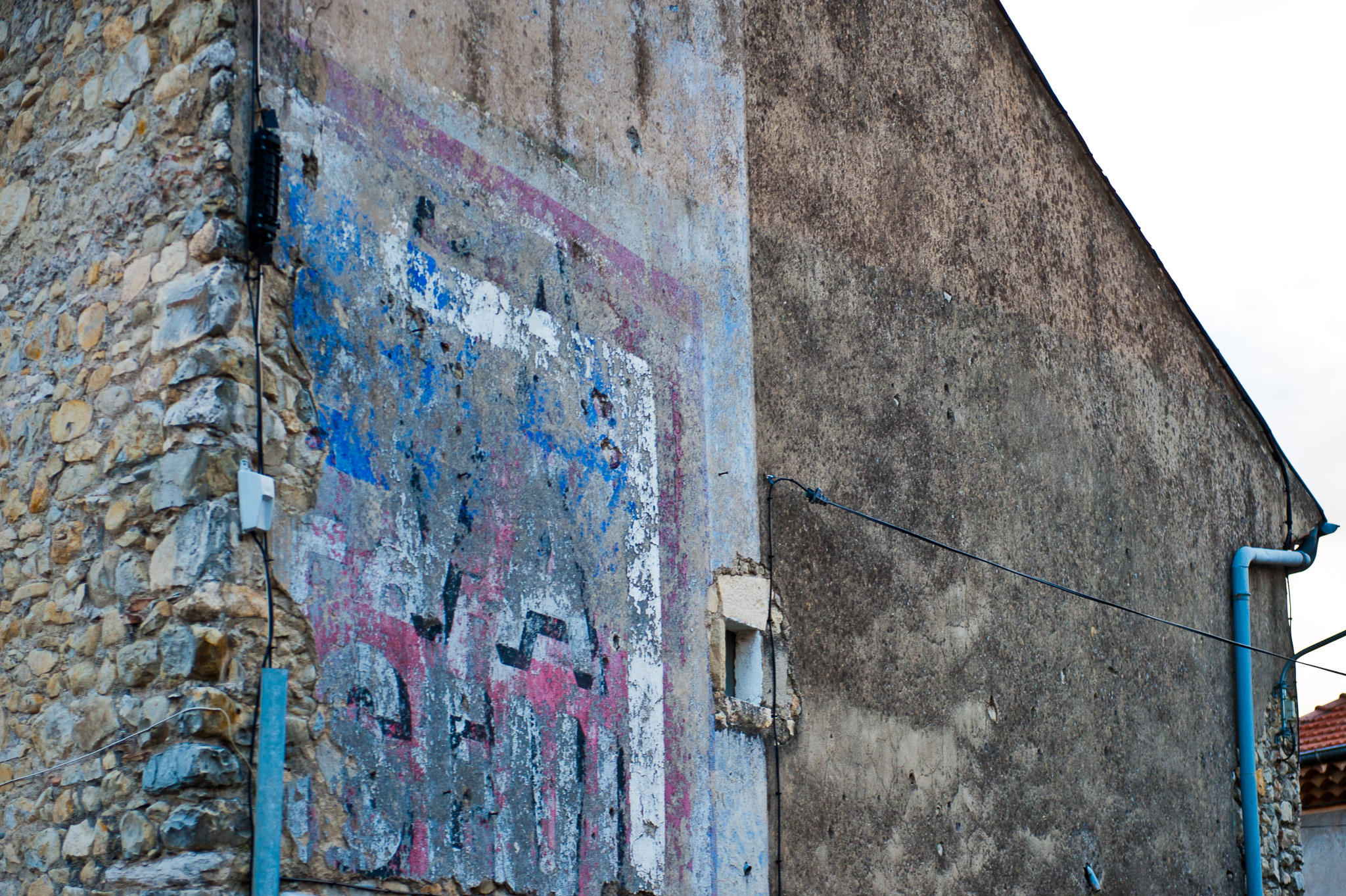 Mur ancien recouvert de papiers déchirés et de traces de peinture colorée