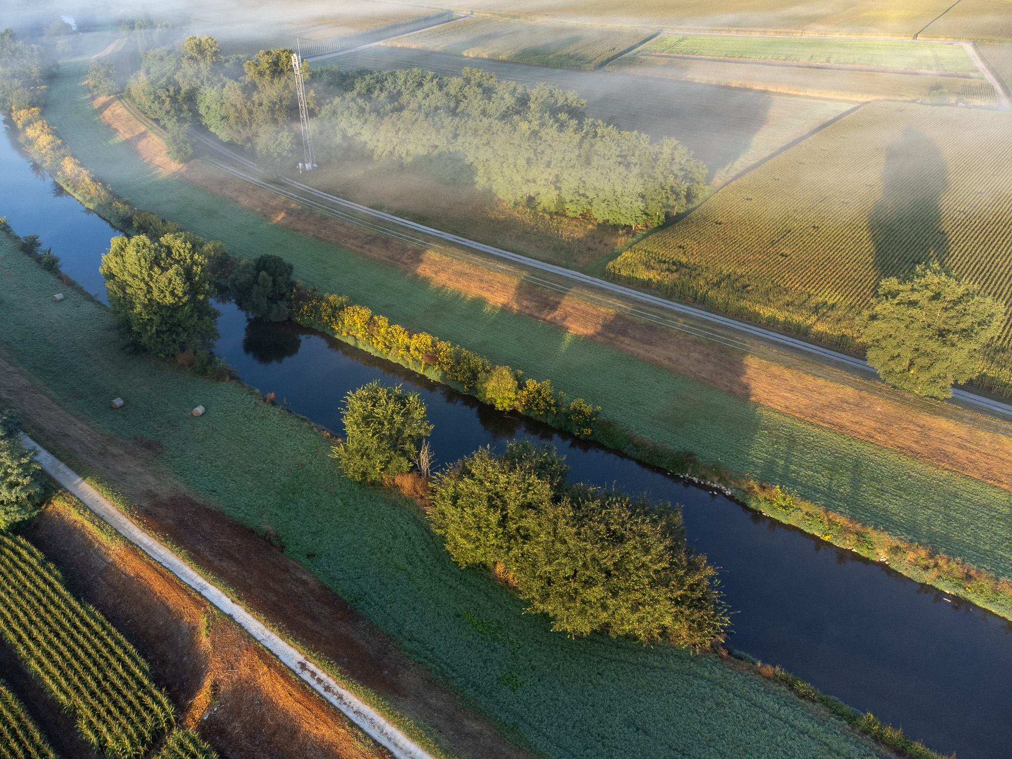 Vue aérienne d’un cours d’eau sinueux entre parcelles agricoles et bosquets