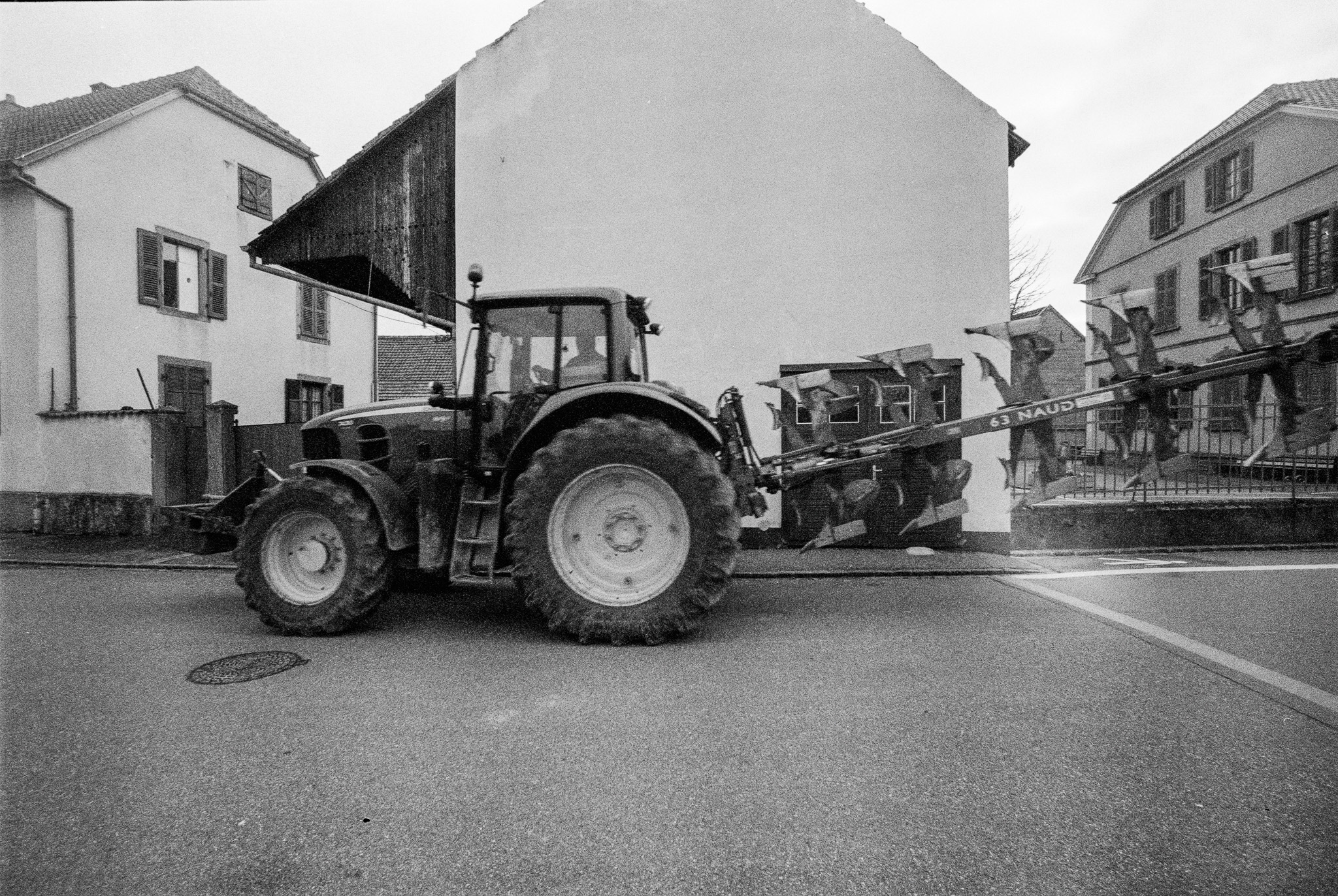 Tracteur circulant dans une rue de Sundhoffen, photographié en noir et blanc