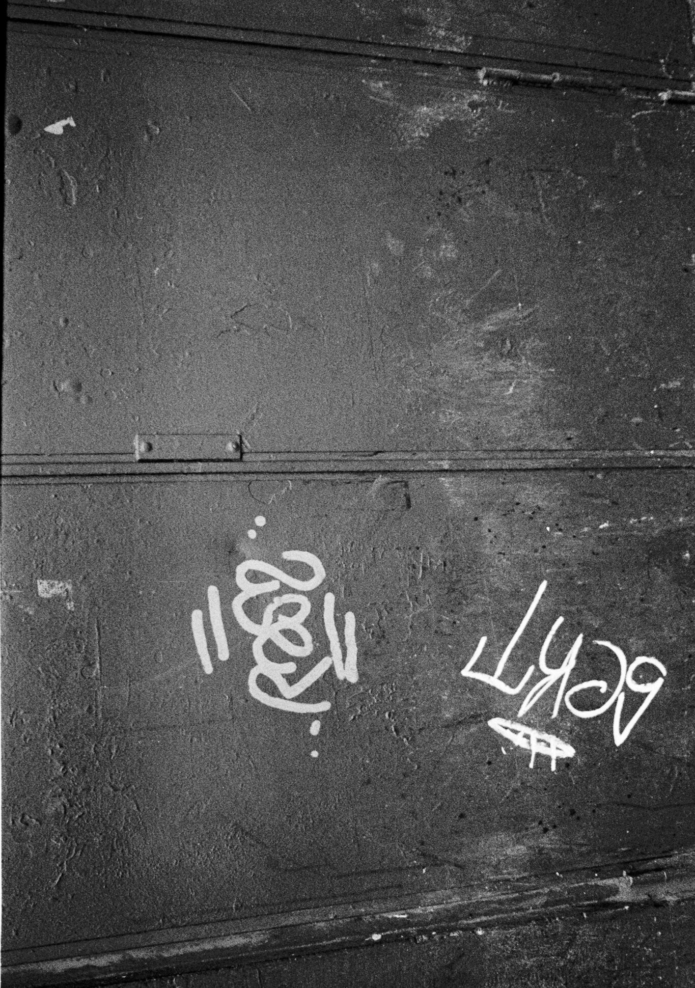 Grande porte métallique sombre portant des inscriptions et des graffitis blancs à Strasbourg