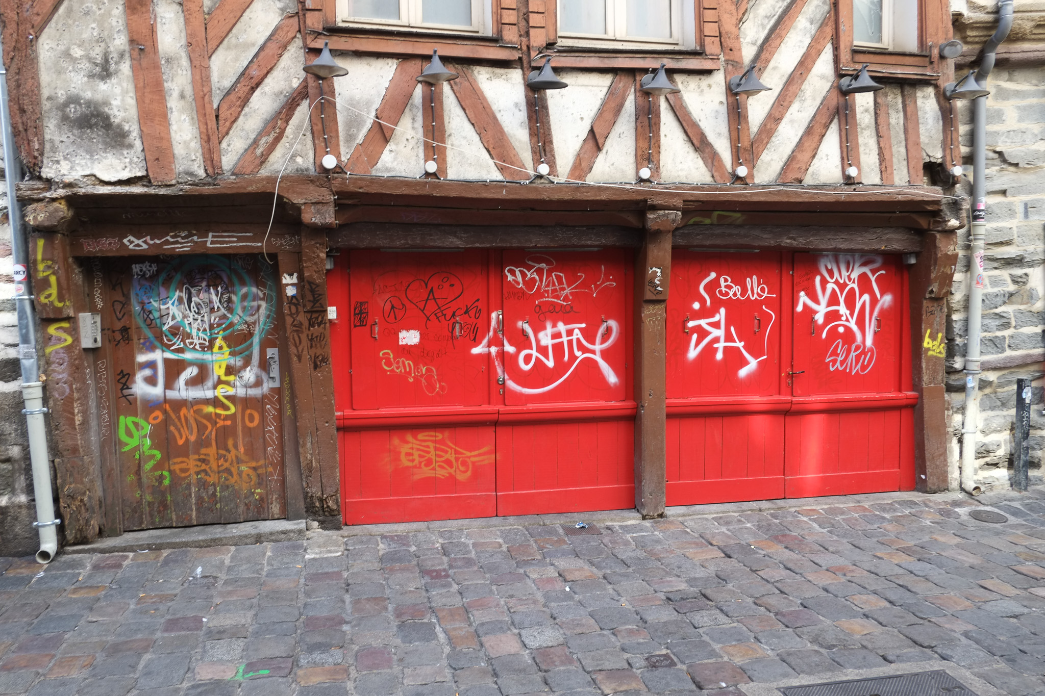Portes rouges couvertes de graffitis sous la façade à colombages d’une maison ancienne
