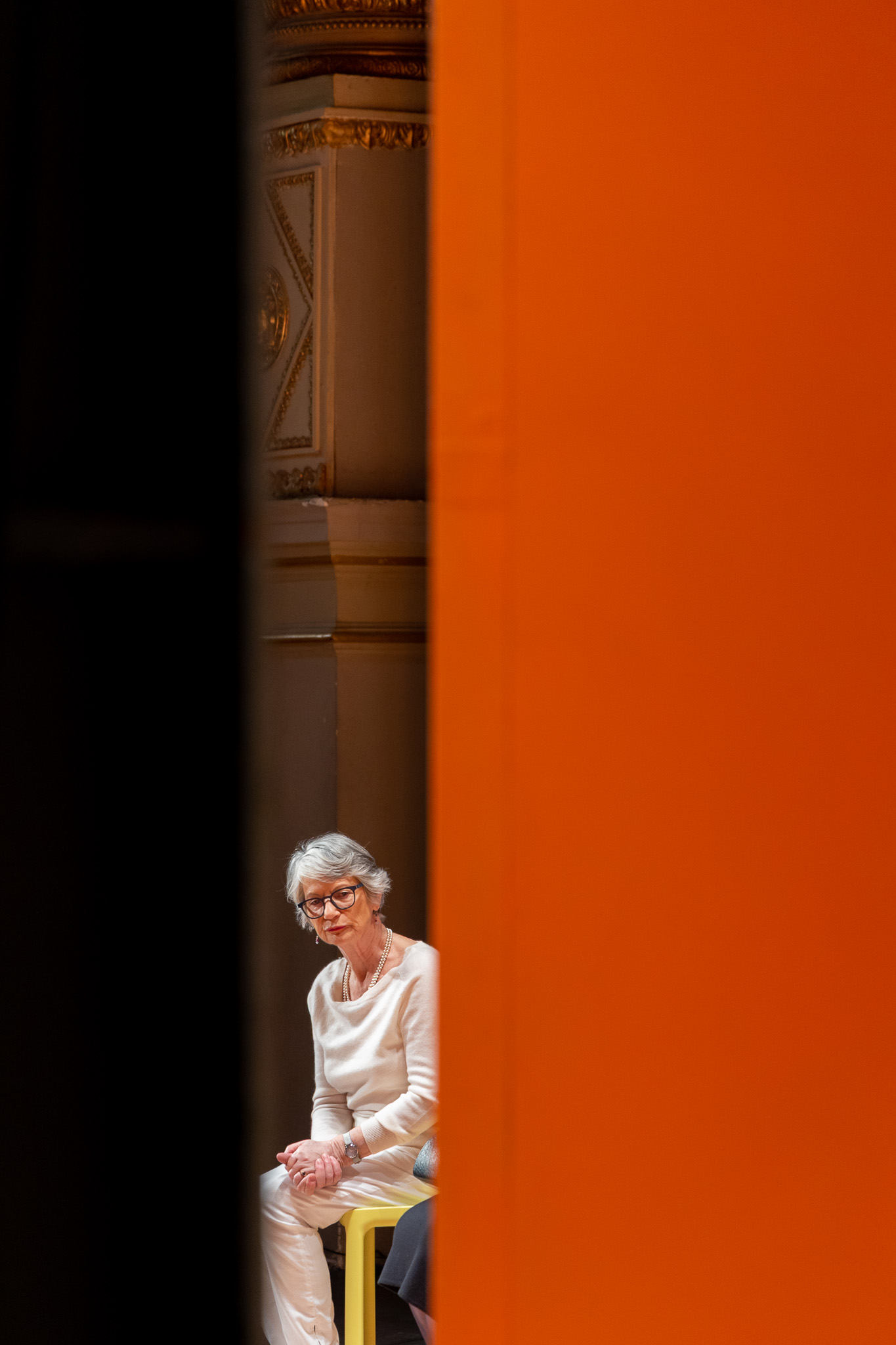 Comédienne en scène photographiée depuis les coulisses à travers le rideau rouge