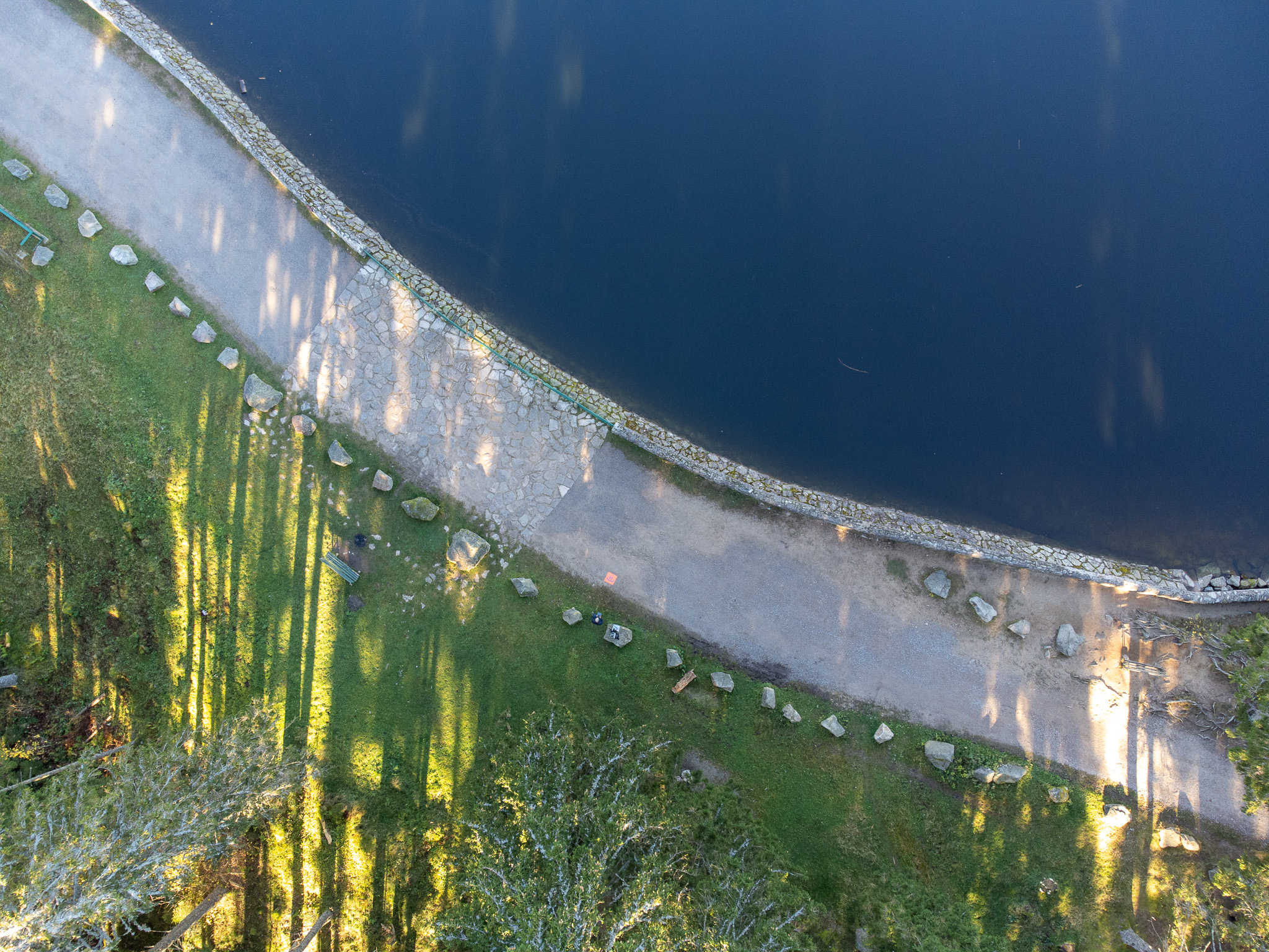Vue verticale d’une digue courbe séparant une étendue d’eau d’un espace végétalisé