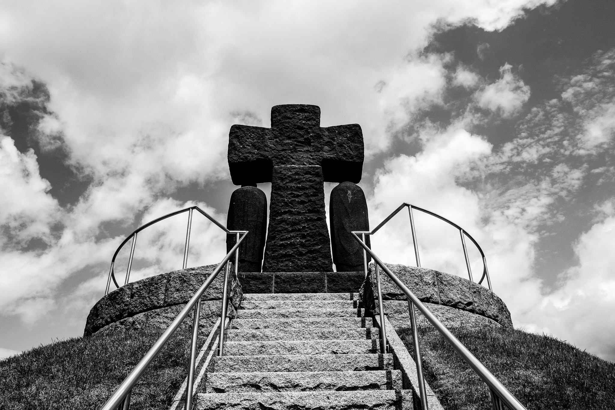 Grande croix sombre au sommet du tumulus central du cimetière militaire allemand de La Cambe