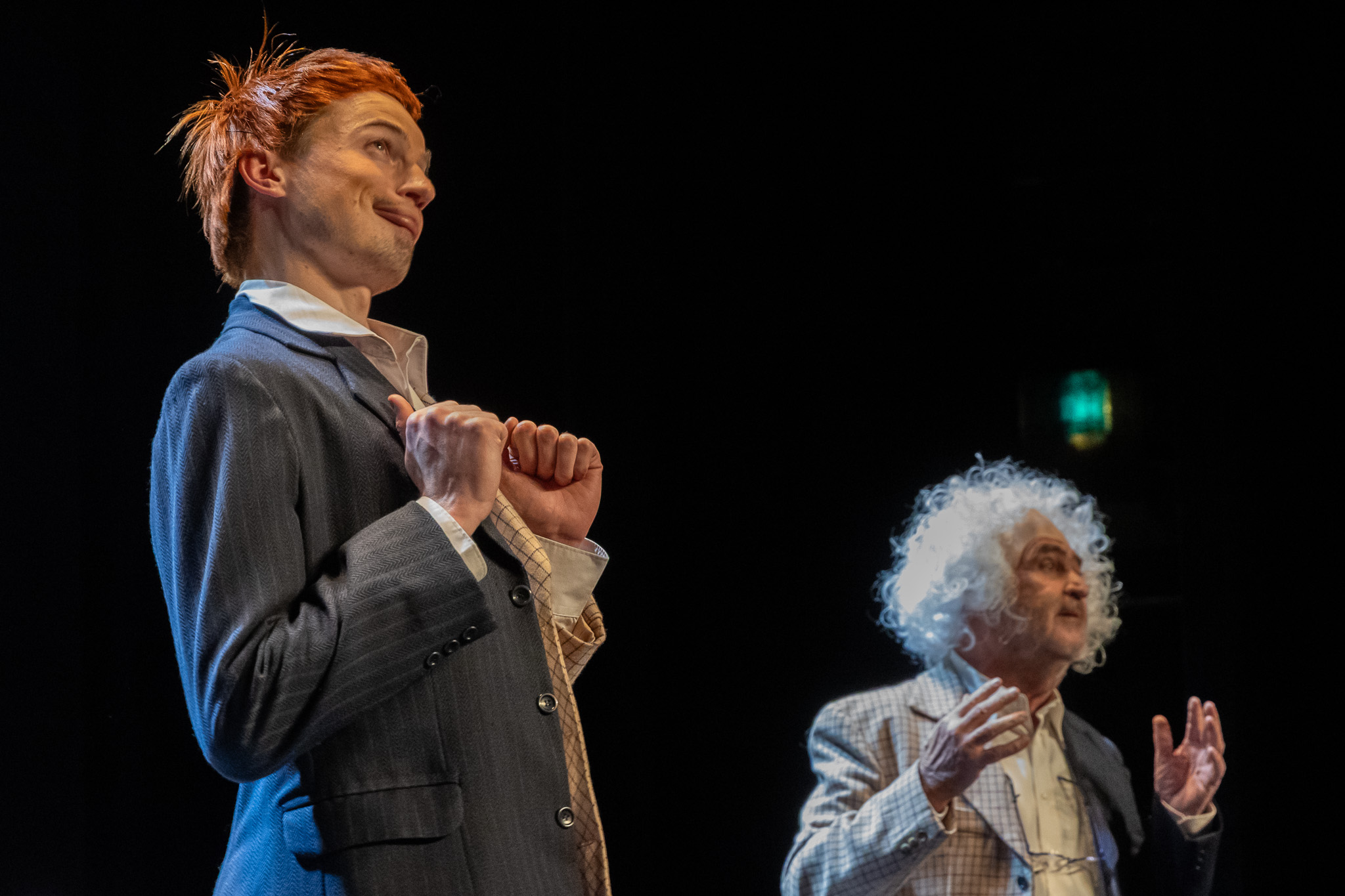 Deux comédiens en costume jouant sur une scène de théâtre sous un éclairage dirigé